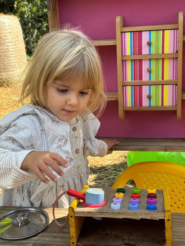 Bambina gioca con un banco da lavoro in legno colorato nella zona dedicata ai più piccoli